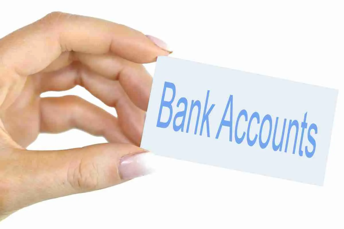 A person's hand holding a card with the words "bank accounts" printed on it.