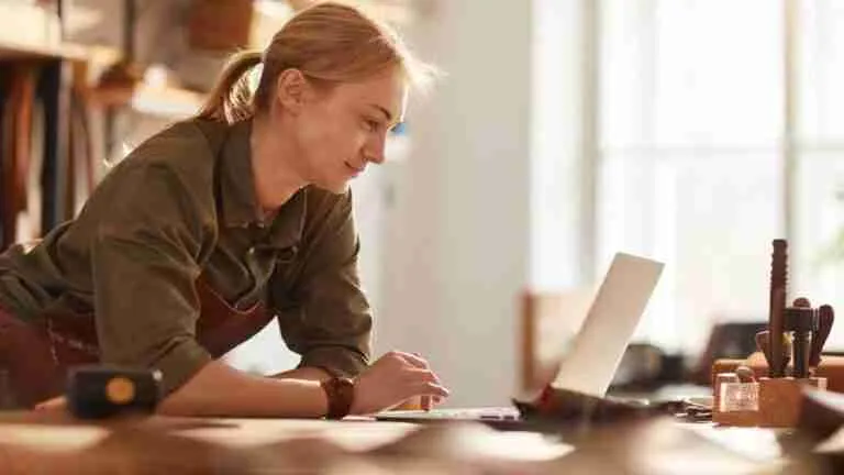 Craftswoman focused on her design plans in a sunlit woodworking studio, contemplating how easy to open bank accounts with bad credit could influence her business.